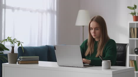 Una-Joven-Estudiante-Está-Trabajando-Con-Una-Computadora-Portátil-En-La-Sala-De-Su-Apartamento-Durante-El-Día-Comunicándose-Por-Chat-En-Un-Usuario-De-Internet-De-Las-Redes-Sociales